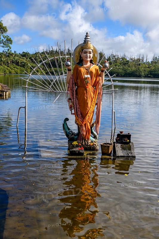 Hindu goddess statue figure sculpture of goddess deity Parvati woman consort Shakti of Lord Shiva Hindu mother goddess mother of Ganesha stands in lake sacred Hindu lake Ganga Talao at religious site largest Hindu sanctuary sanctuary for religion Hinduism outside of India for devout Hindu Hindus