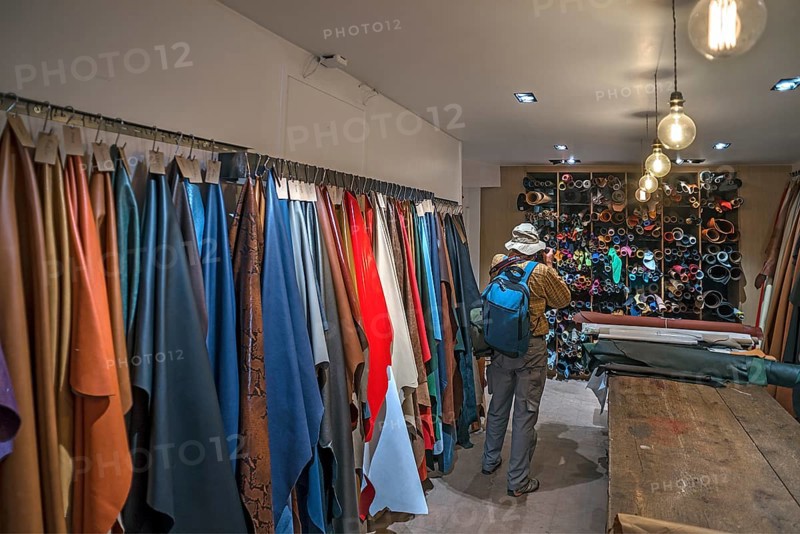 Tourist taking pictures of the leather shelves in a saddlery with permission