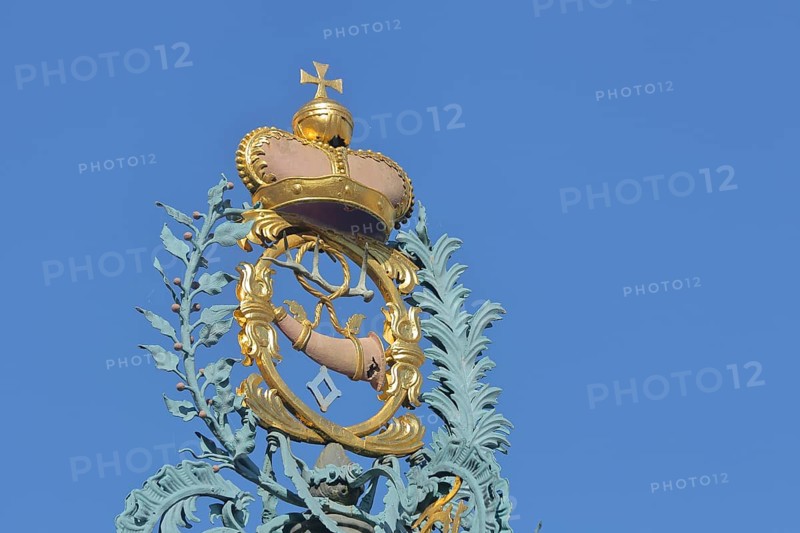Golden crown with imperial orb and post horn with ornaments at the market fountain