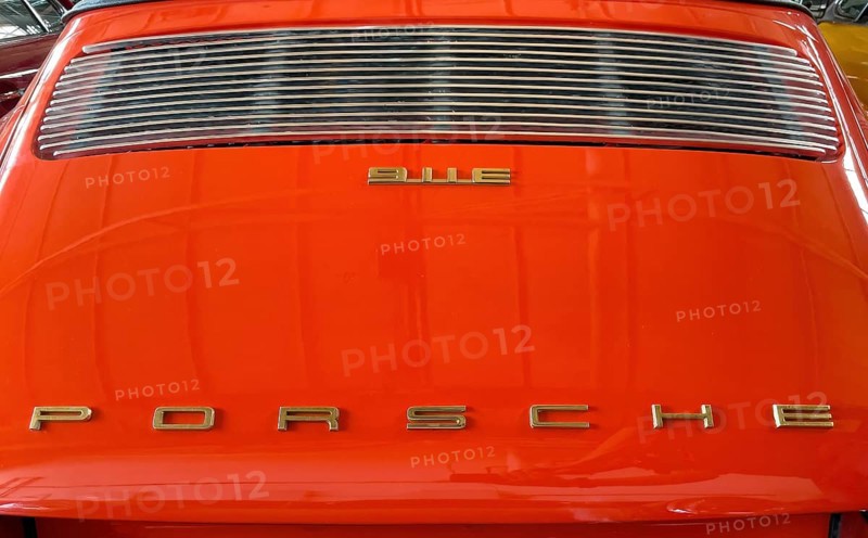 Rear of classic car Porsche 911 E from the 60s in orange colour with typical radiator grille