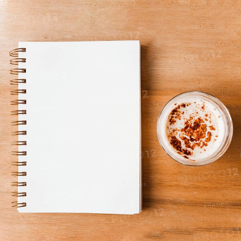 Closed white spiral notebook coffee glass with cocoa powder