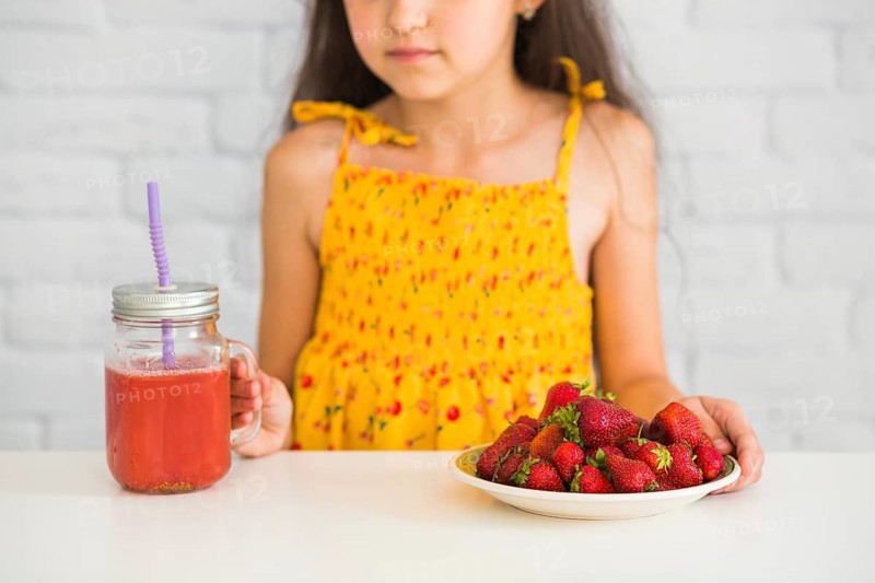 Close up girl holding plate strawberries smoothies jar