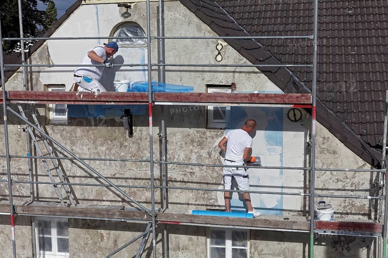 Painters on scaffolding plastering the facade of a house from 1830
