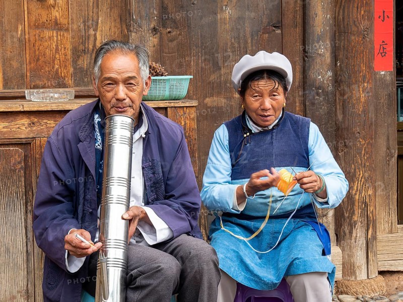 Old Chinese couple sitting in front of wooden house