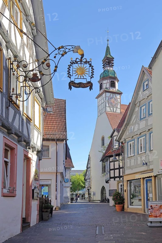 View through alley to Nikolauskirche and nose sign of Gasthof Zur Sonne