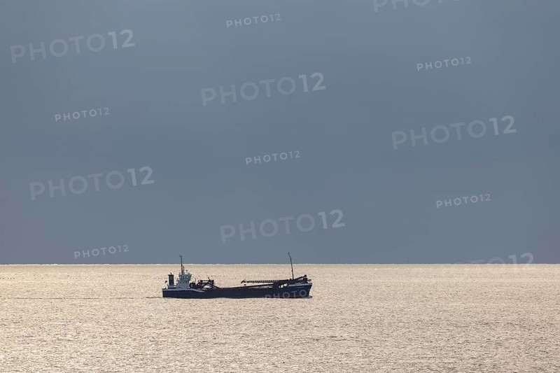 Dark clouds and sunlight over the North Sea plus freighter