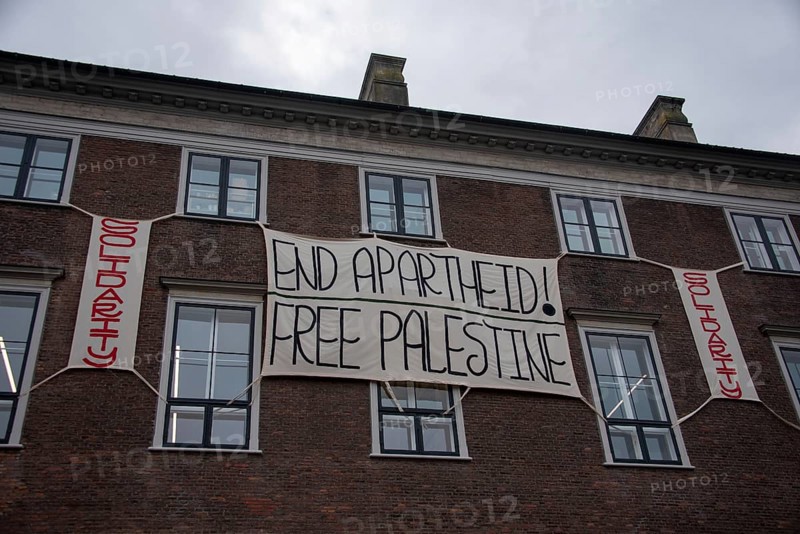 A banner with the words End Apartheid! hangs on a building. Free Palestine