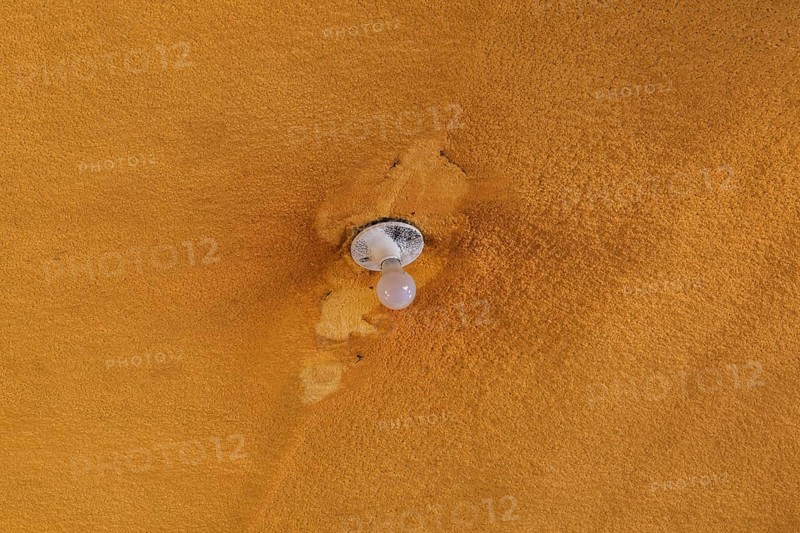 Lightbulb and socket on ceiling covered with foam insulation