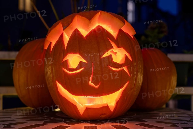 Carved pumpkin stands on a balcony on Halloween evening