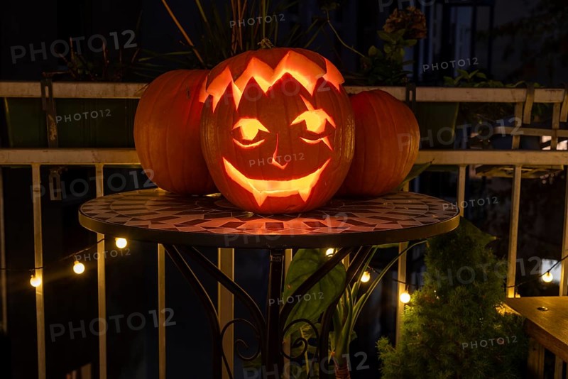 Carved pumpkin stands on a balcony on Halloween evening