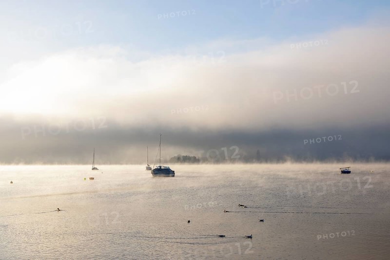 Fog over Lake Constance on an autumn morning with boats
