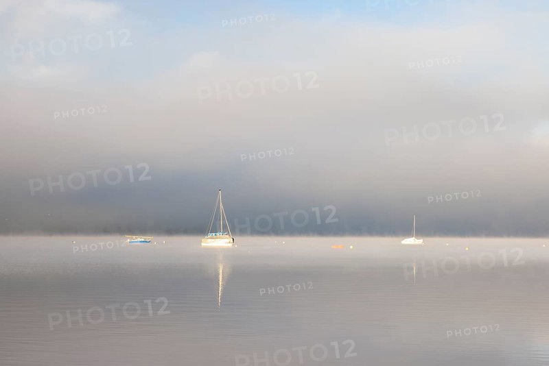 Fog over Lake Constance on an autumn morning with boats