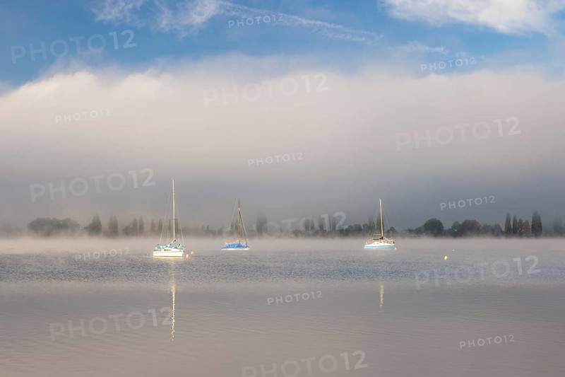 Fog over Lake Constance on an autumn morning with boats