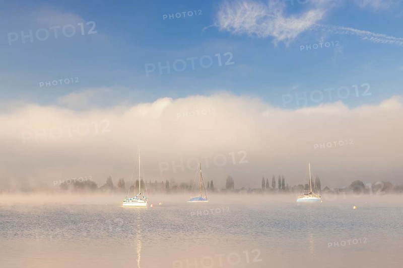 Fog over Lake Constance on an autumn morning with boats