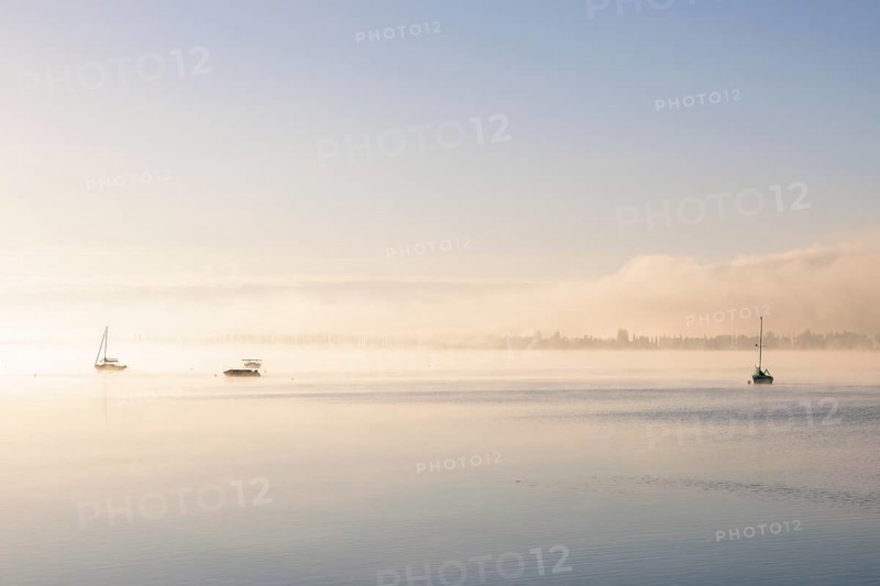 Fog over Lake Constance on an autumn morning with boats