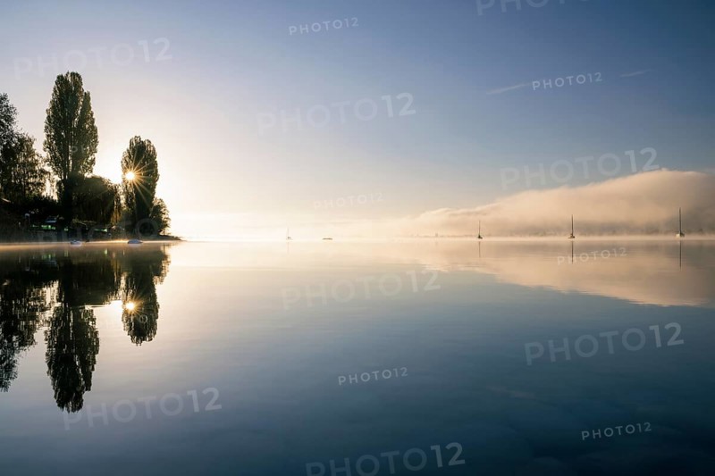 Fog over Lake Constance on an autumn morning with boats