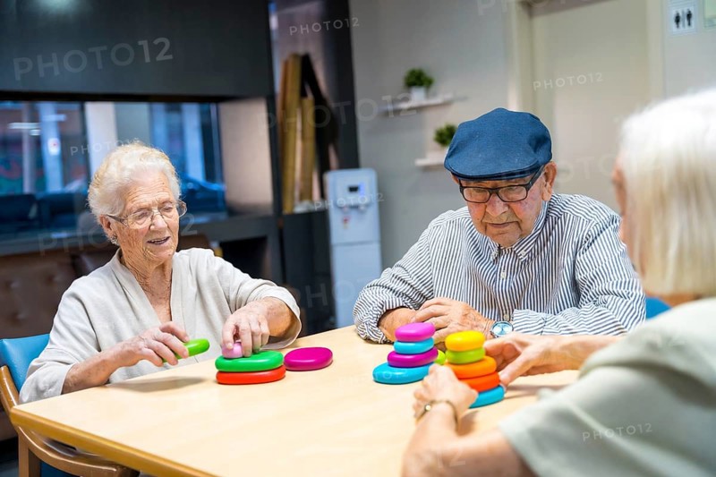 Three cute elder people playing skill games together in a nursing home