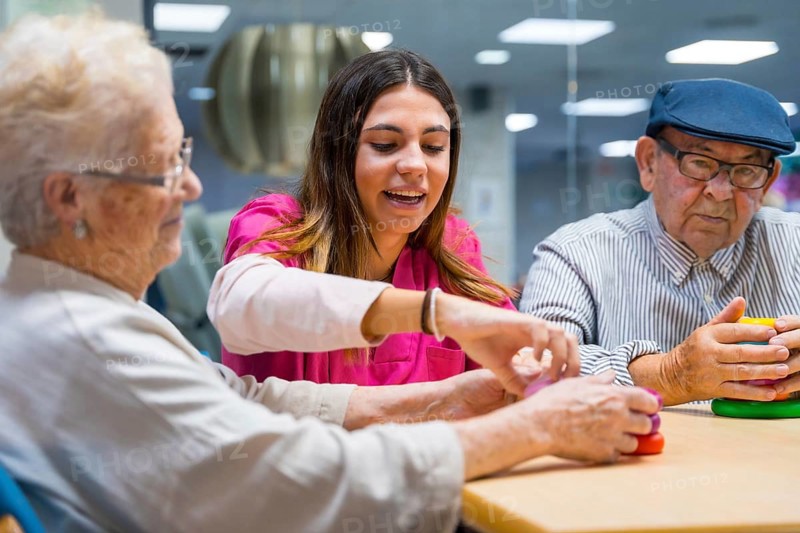 Friendly nurse supervising senior people playing skill games in nursing home