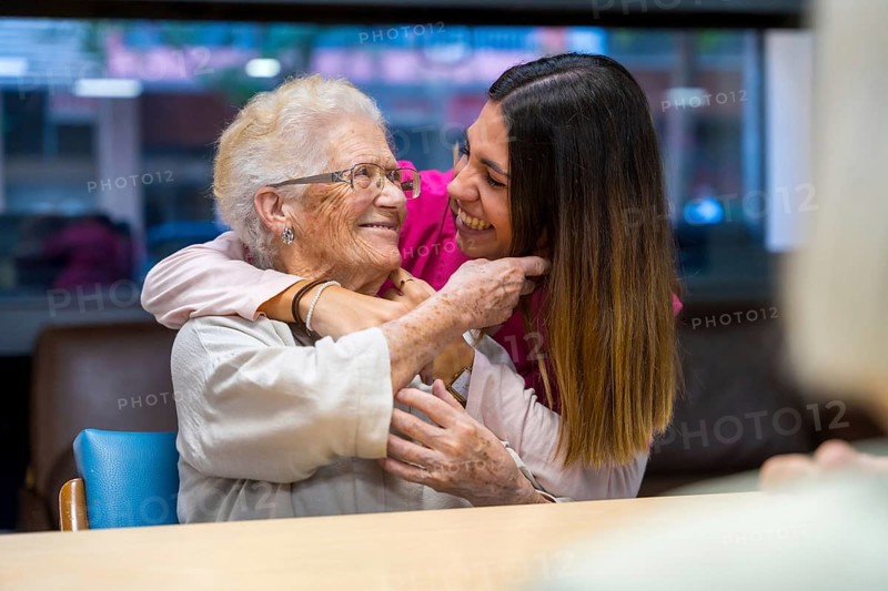 Happy moment of an elder woman and nurse embracing in a geriatric