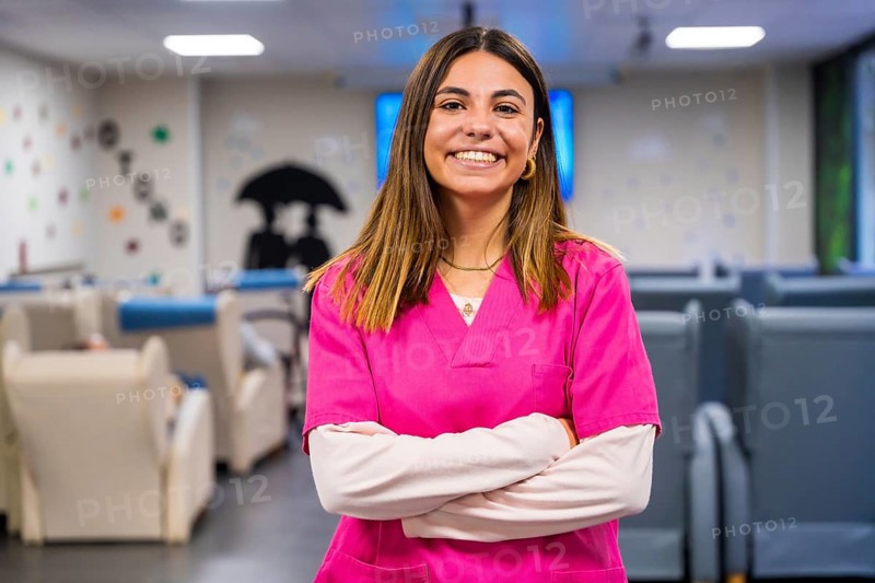 Portrait of a happy nurse standing with arms crossed in a geriatric