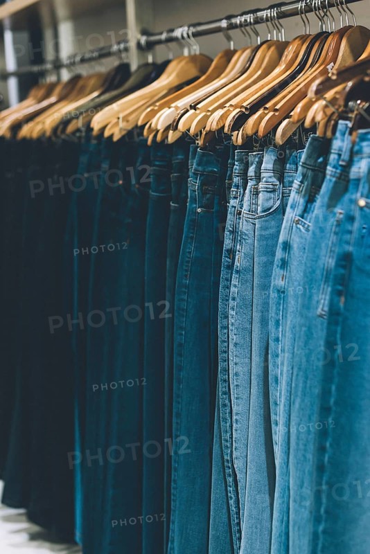Jeans hanging on a rack in a store. Copy space. Vertical shot