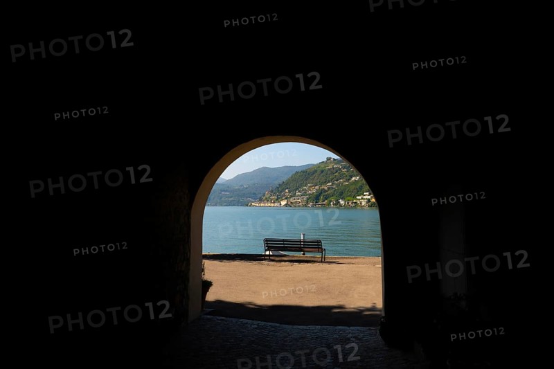 Old Beautiful Street Tunnel with Arch and a Bench From Brusino Arsizio on the Waterfront in a Sunny Summer Day and with Lake Lugano and Mountain View over Morcote