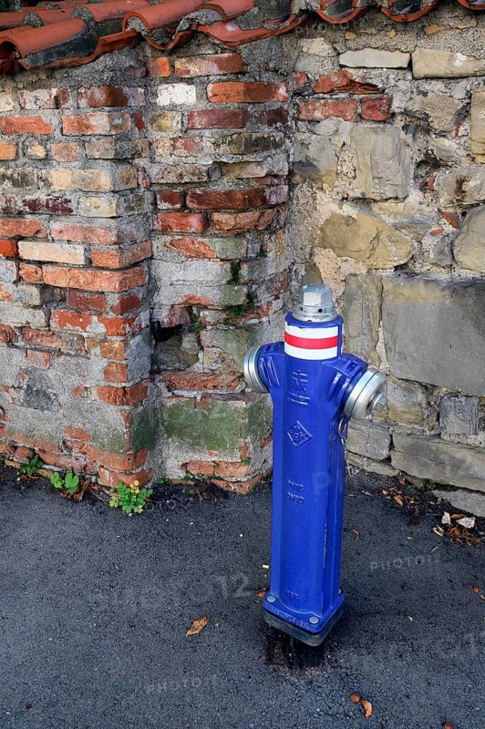 Blue hydrant in front of city wall