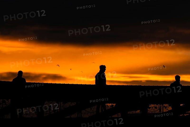 A passer-by crosses the Eiserner Steg in Frankfurt am Main at sunset