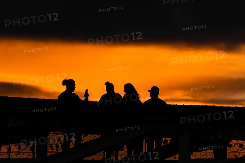 Passers-by watching and photographing the sunset from the Eiserner Steg in Frankfurt am Main