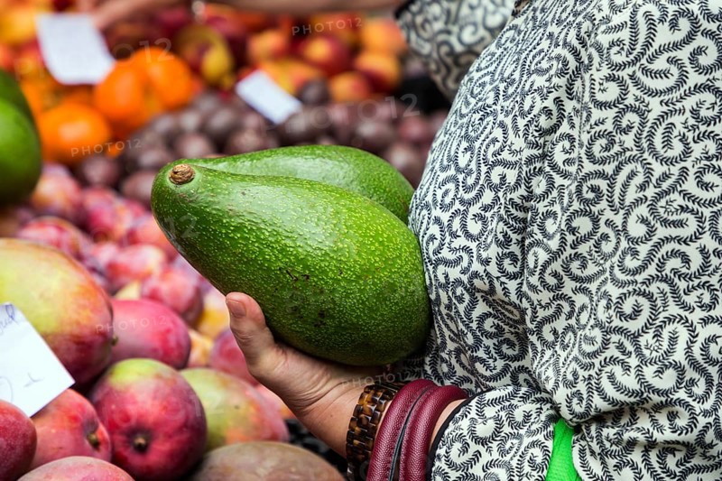 Woman holding two large avocado