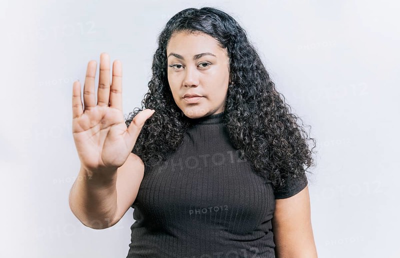 Close up of woman gesturing stop with the palm of hand isolated. People gesturing stop isolated. Latin woman gesturing stop with palm hand isolated