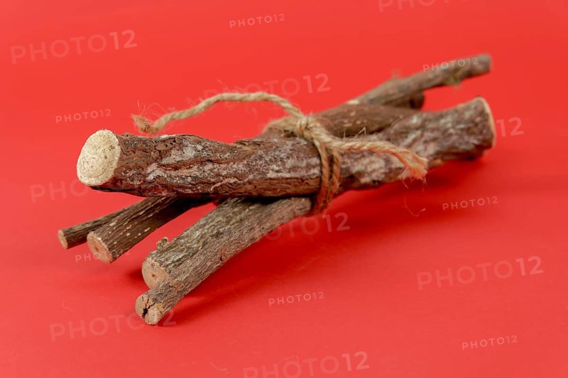 Pile of licorice roots tied with a rope isolated on red background