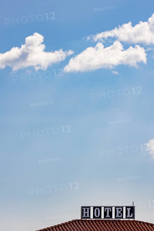 Roof of a hotel in sunshine against a blue sky with the advertising lettering Hotel