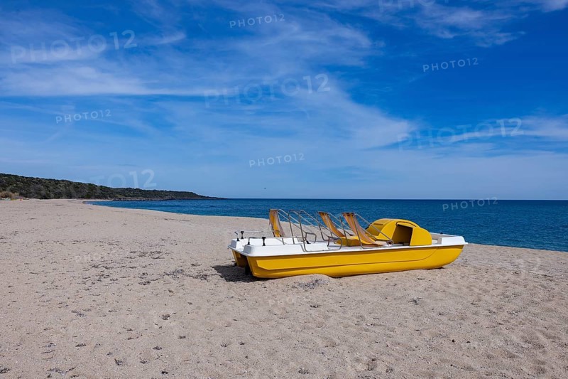 Yellow pedal boat on the beach with blue sky and blue sea