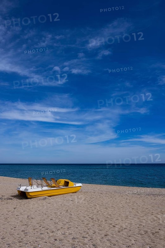 Yellow pedal boat on the beach with blue sky and blue sea