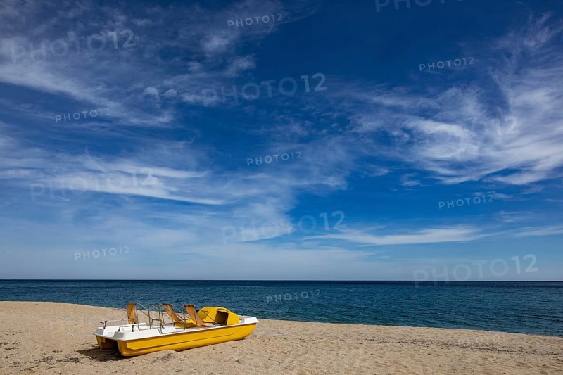 Yellow pedal boat on the beach with blue sky and blue sea