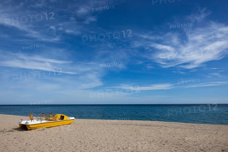 Yellow pedal boat on the beach with blue sky and blue sea