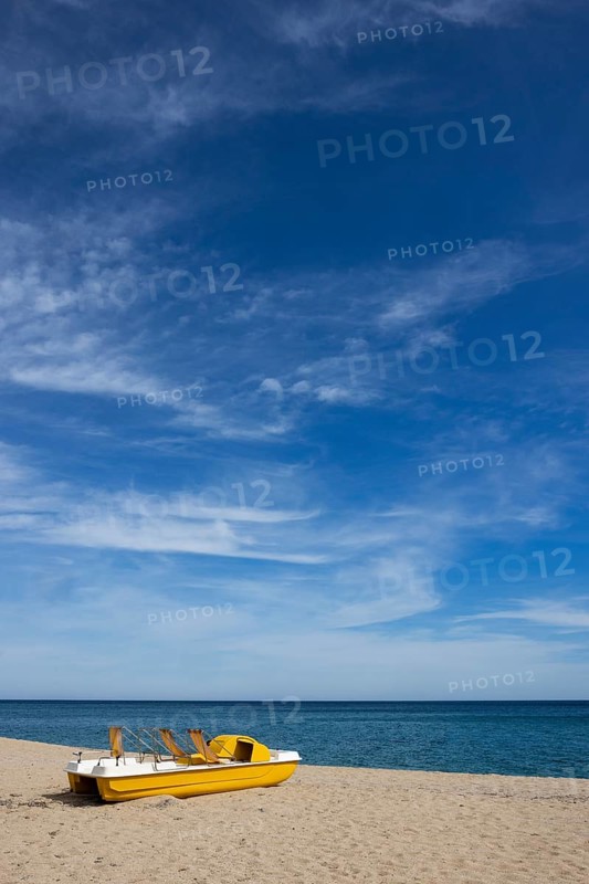 Yellow pedal boat on the beach with blue sky and blue sea