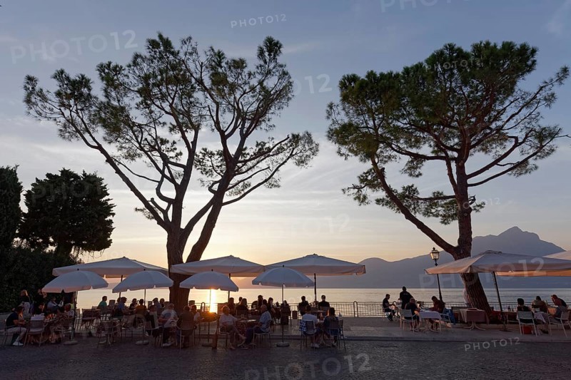 Restaurant terrace under pine trees on the lake shore at sunset