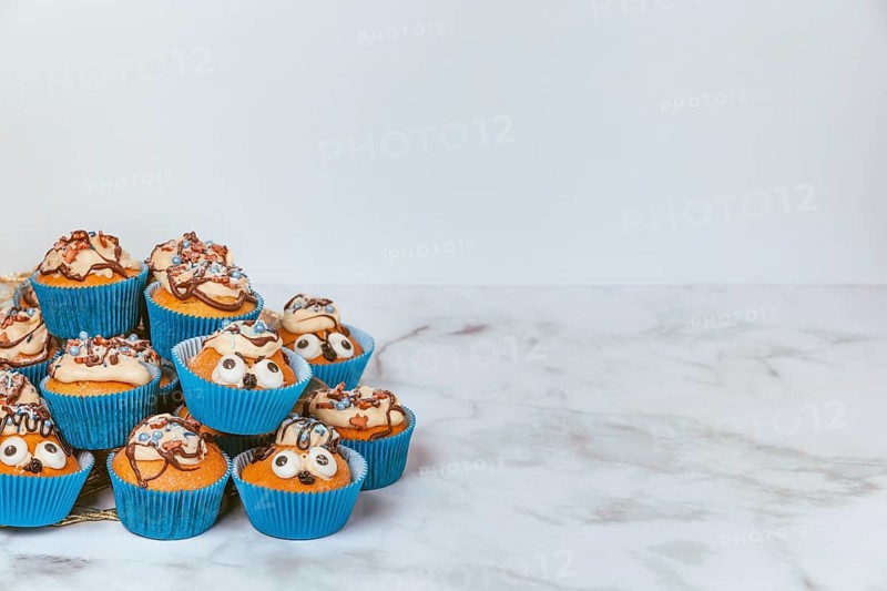 Muffins in blue ramekins with chocolate icing and sugar sprinkles