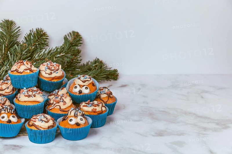 Muffins in blue ramekins with chocolate icing and sugar sprinkles