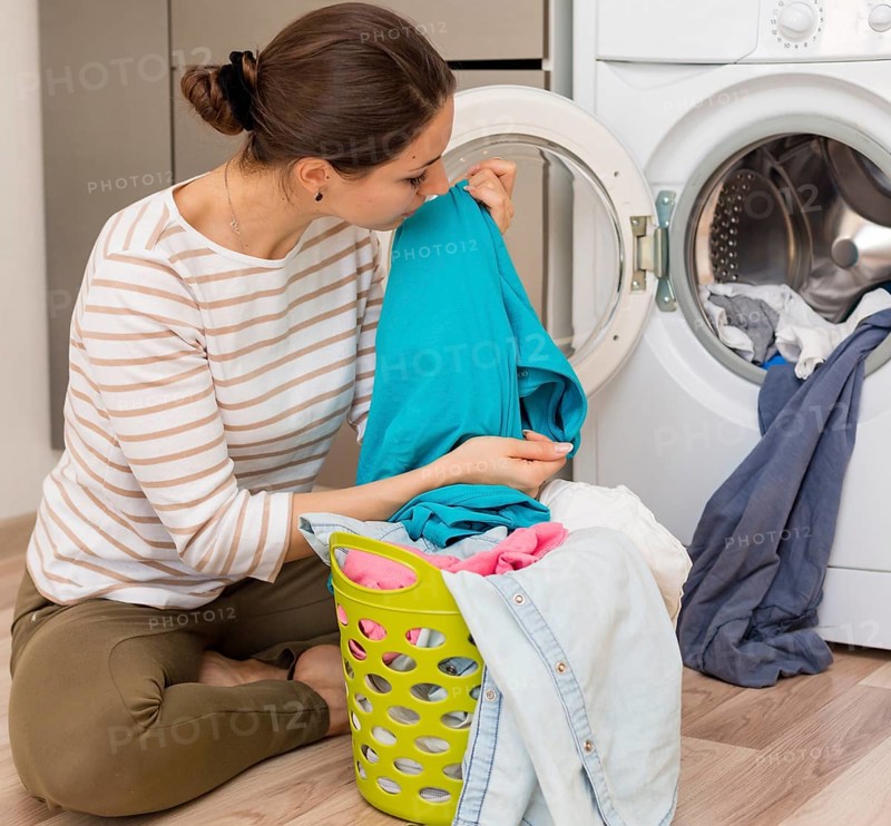 Casual woman smelling clean laundry