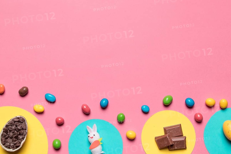 Choco chips rabbit statue chocolate pieces colorful candies pink backdrop with space text