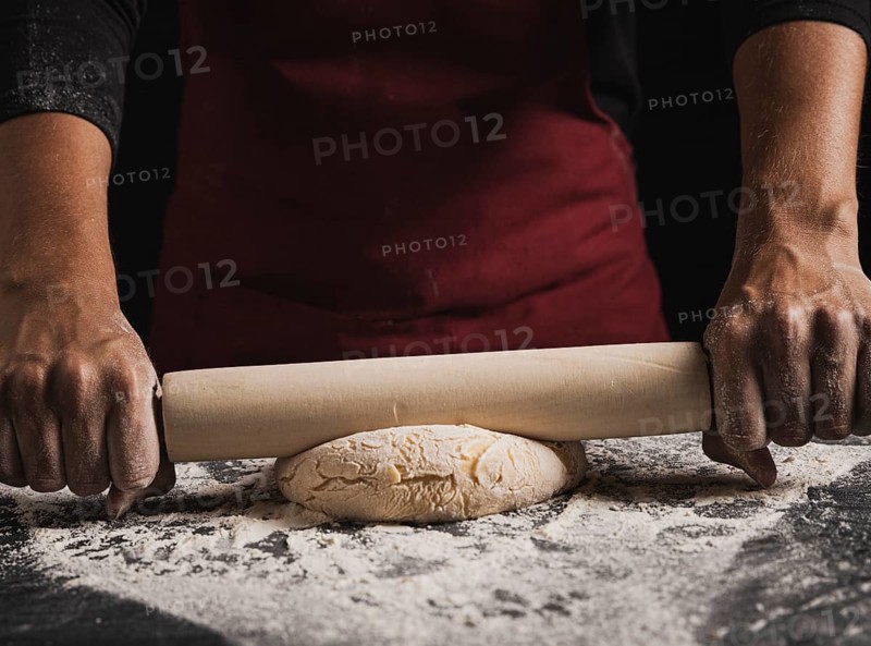 Close up baker rolling dough composition