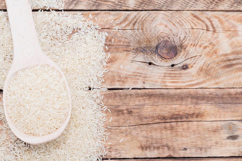 Close up raw white rice spoon textured plank