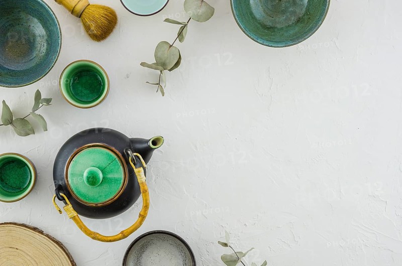 Elevated view teapot bowl tea cup brush isolated white backdrop
