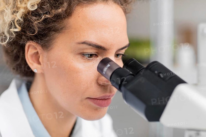 Female researcher laboratory looking through microscope
