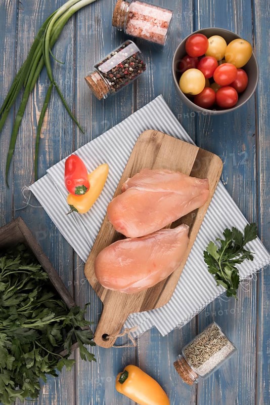 Flat lay chicken breast wooden board with peppers tomatoes