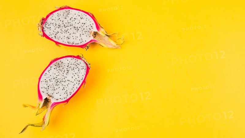 Halved dragon fruit yellow background