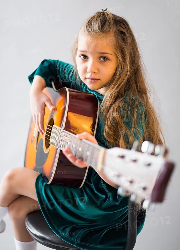 Little girl dress playing acoustic guitar